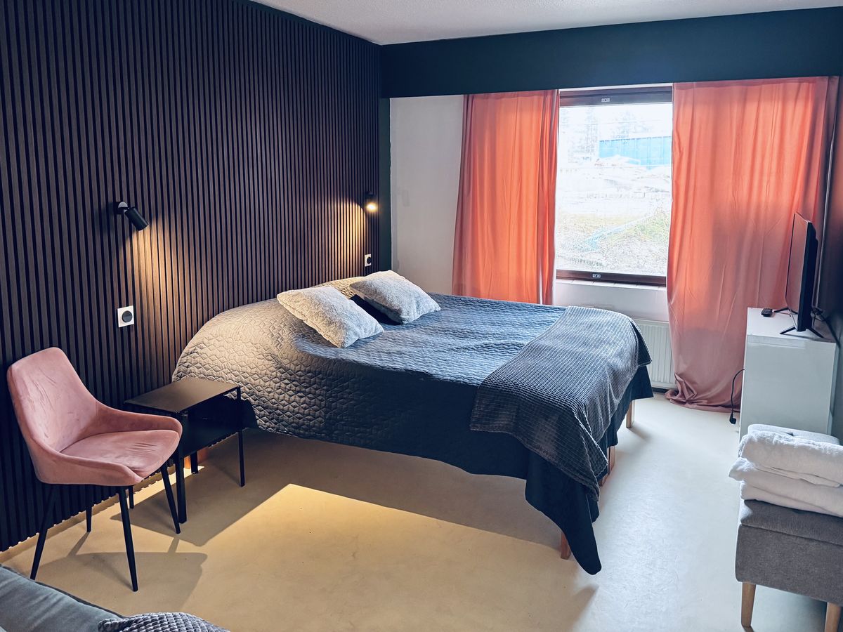 Hotellihuone, parisänky puusäleseinää vasten ja ikkuna
